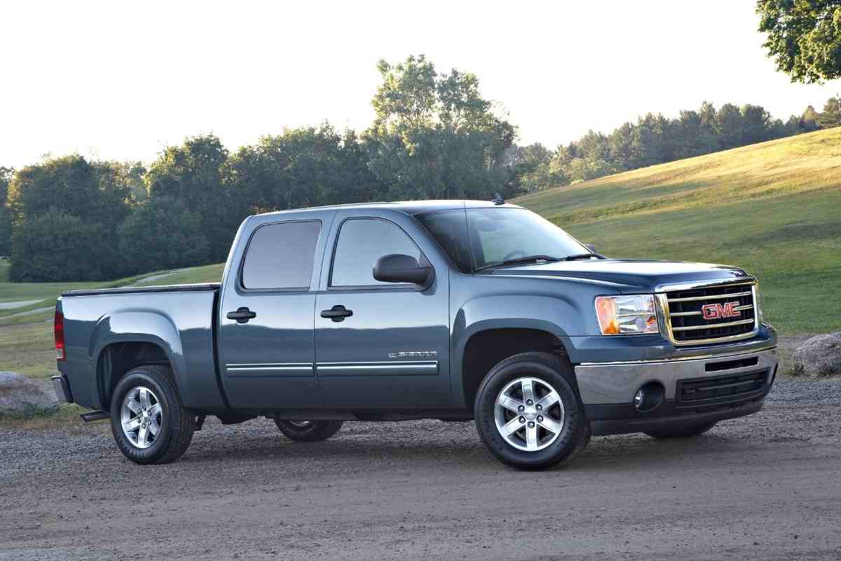 Image for "how much does it cost to paint a GMC Sierra?" shows a dark gray GMC Sierra against a grassy hill