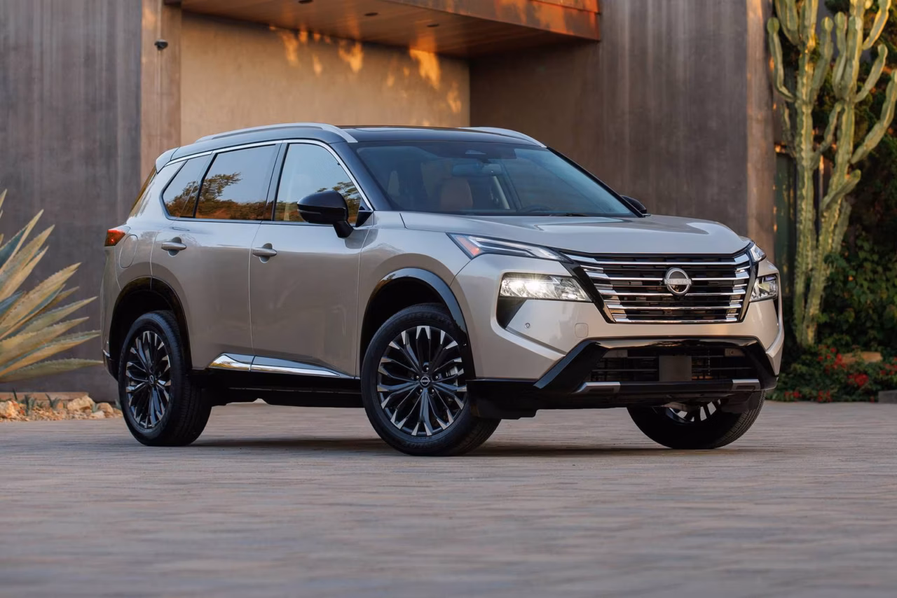 The 2025 Nissan Rogue is one of the leaders in the list of what are the best years for the Nissan Rogue. The image shows a sand-colored nissan Rogue in front of a concrete building in a desert scenario 