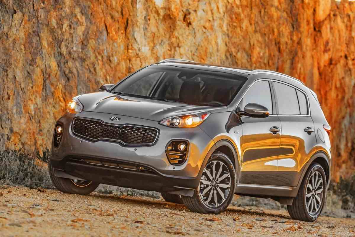 Image for "Can a Kia Sportage be flat towed?" shows a dark gray Kia Sportage at a profile, in front of a rocky background