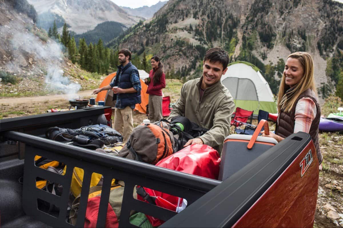 How Much Weight Can A Chevy Colorado Hold In The Bed? 1 Image of four people camping while loading the back of a Chevy Colorado is the image used for How Much Weight Can A Chevy Colorado Hold.