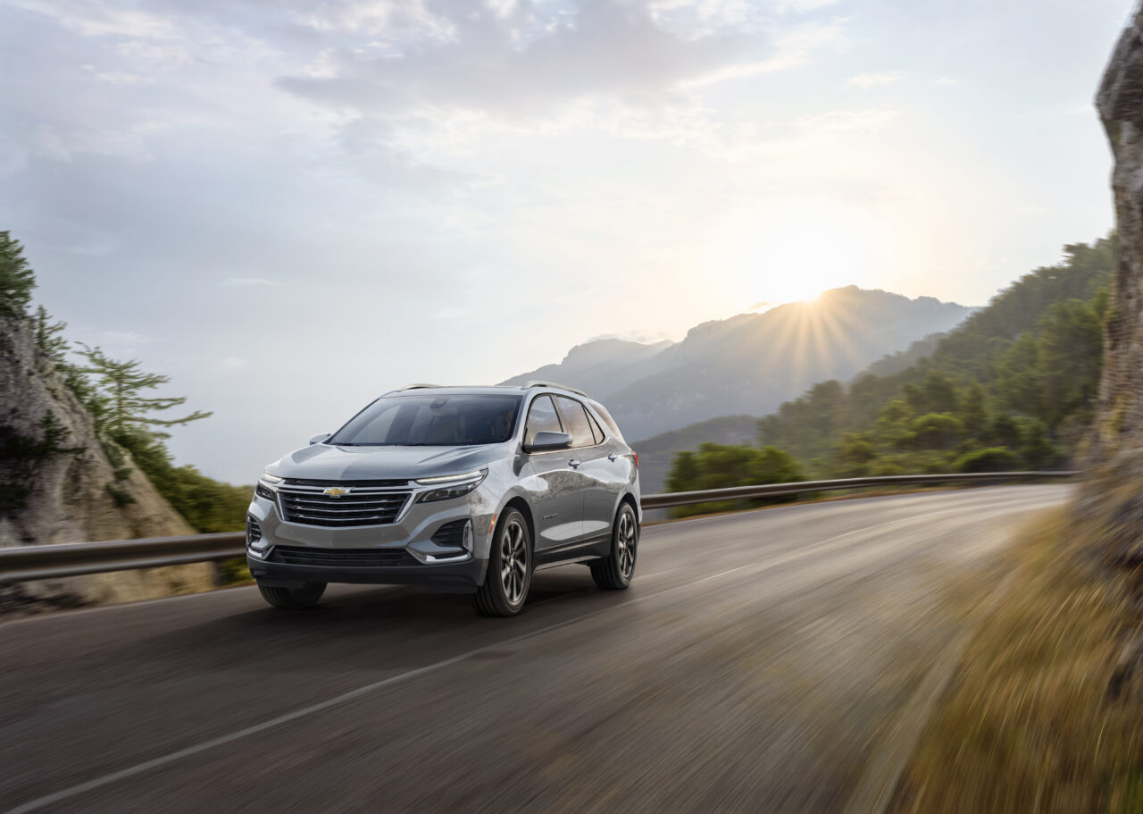 Front 3/4 view of Chevrolet Equinox Premier in Sterling Gray Metallic driving on mountain road.