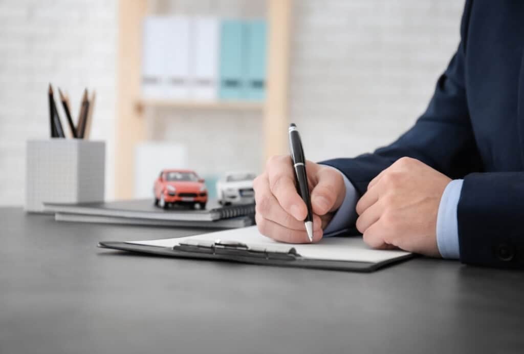 How Much Does Car Insurance Cost In 2026? 1 how much does car insurance cost? Generic image shows a man writing on a paper