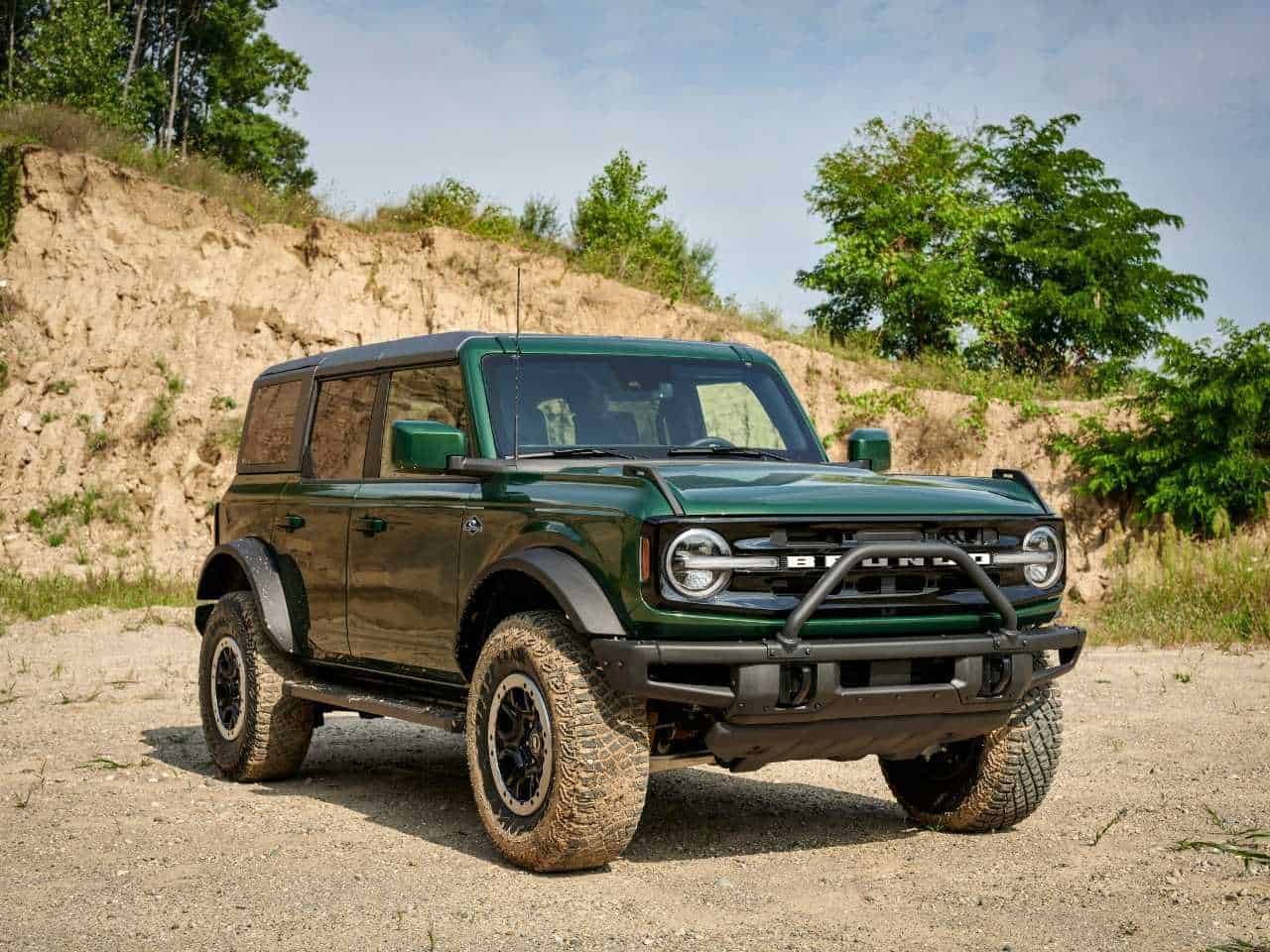 A dark green 2022 Ford Bronco stands in front of a dusty, rocky terrain. It's one of the best Ford Bronco years. 