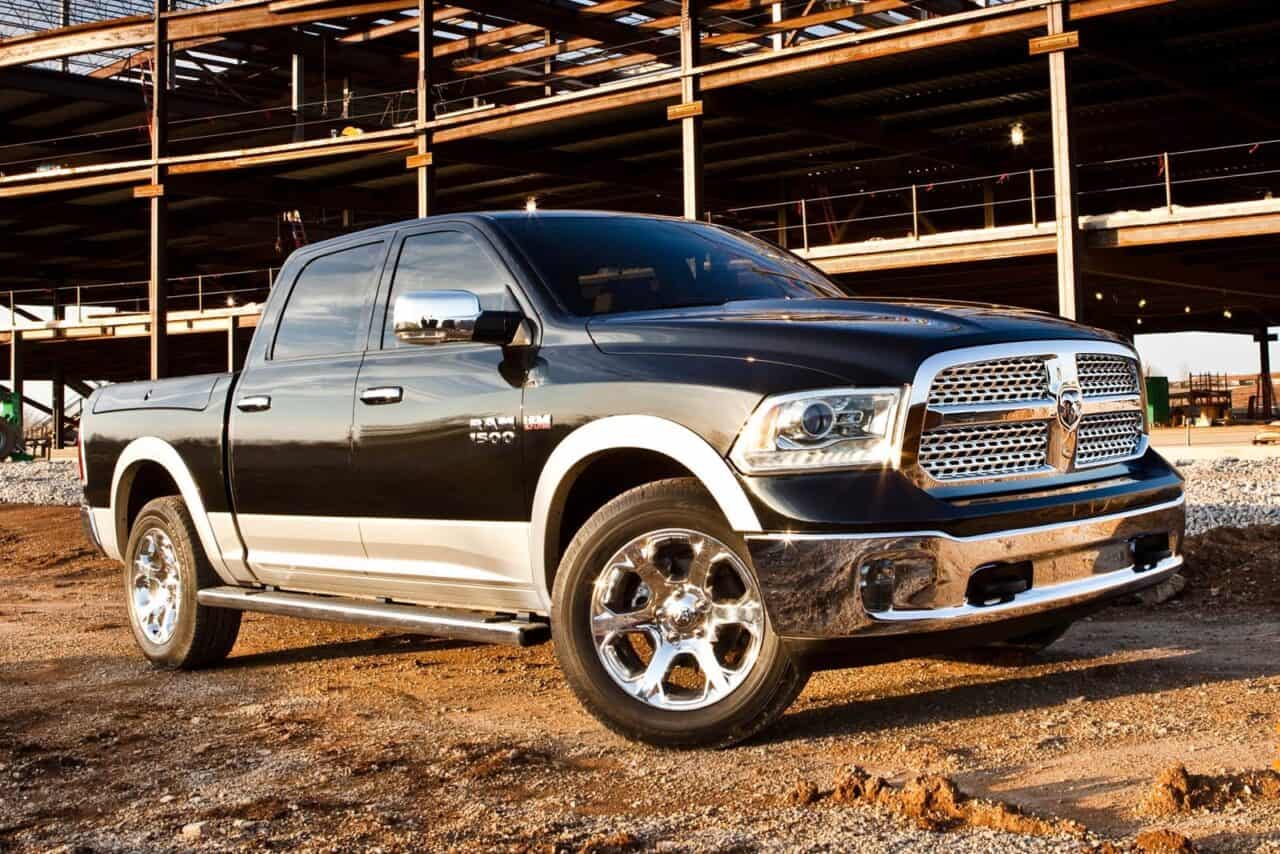 The 2013 model is the best year for the Dodge Ram 1500, such as the one in the image, which is black with silver cladding, and it's parked in front of a construction. 