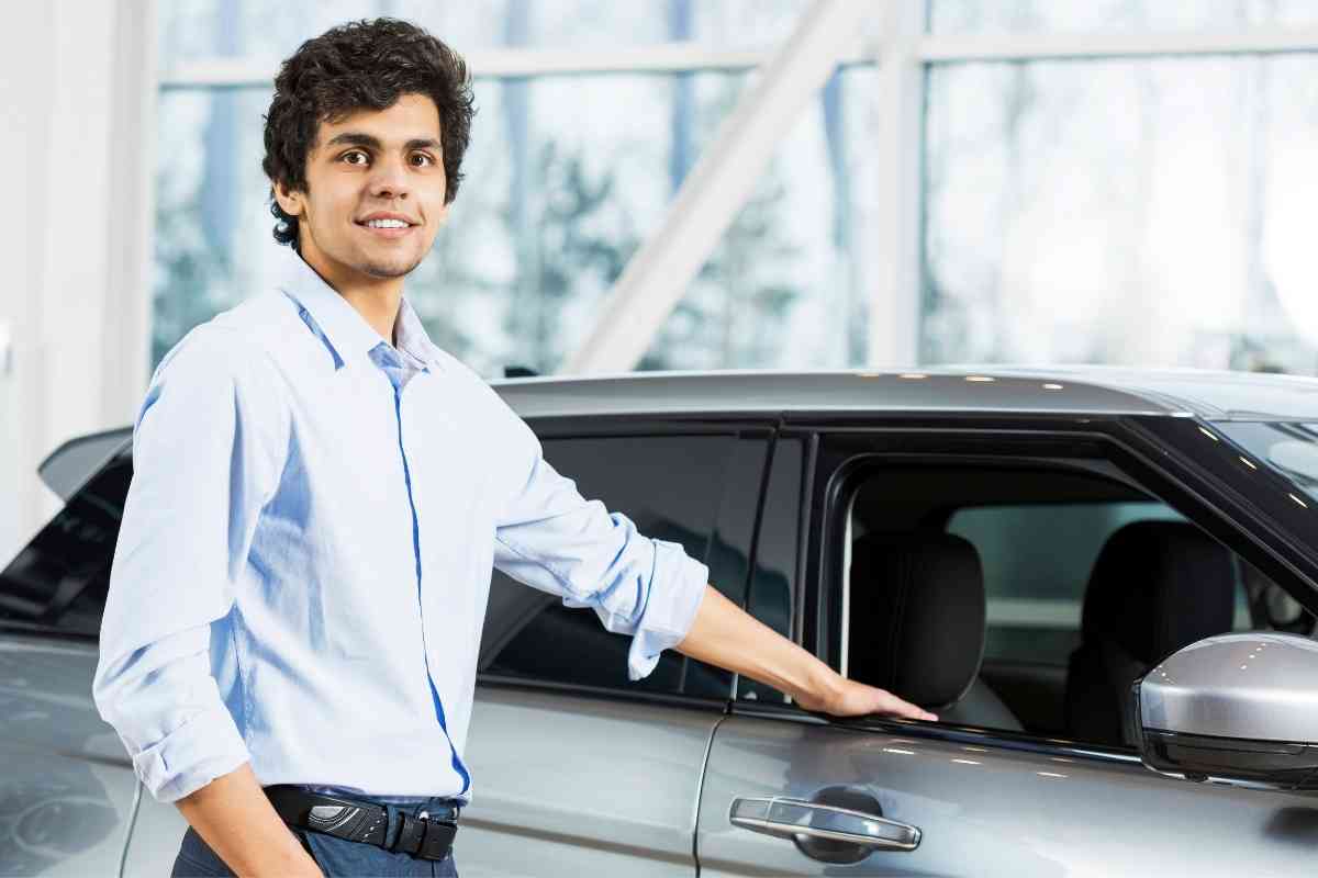 image for: lower monthly car payments shows a young person resting his hand on the window edge of a new car
