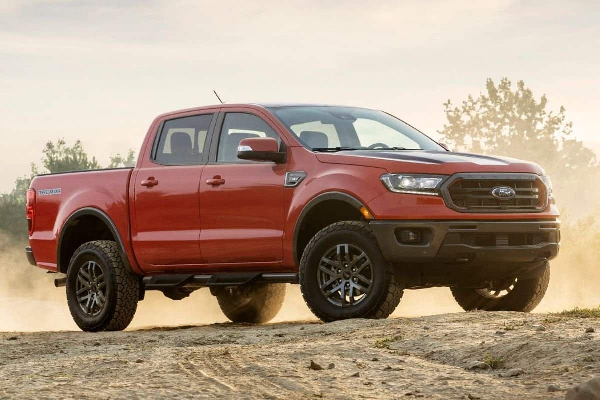 A red Ford Ranger similar to those affected by the Ford Recall is in front of a dusty trail 