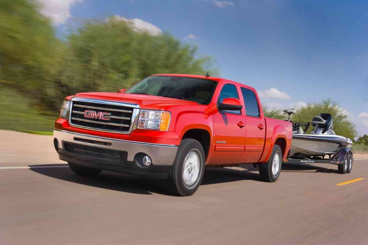 Image for "what to look for when buying a used GMC Sierra" shows an older model GMC Sierra towing a boat
