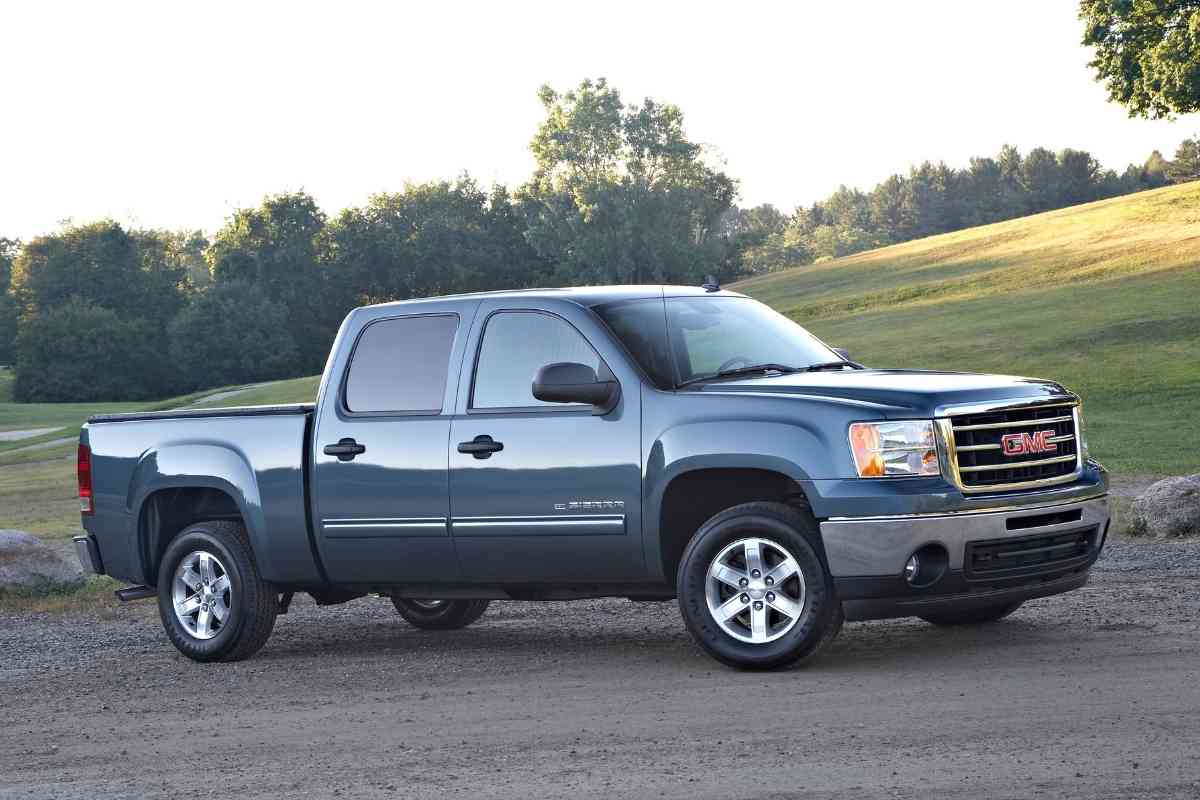 What to look for when buying a used GMC Sierra? The image shows a dark blue GMC Sierra against a grass field