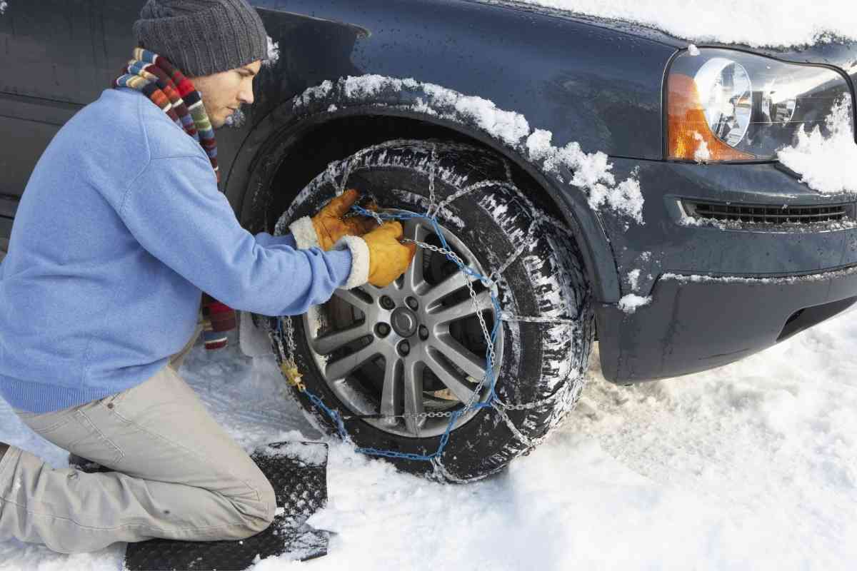How do snow chains work? Photo of man installing snow chains on his vehicle