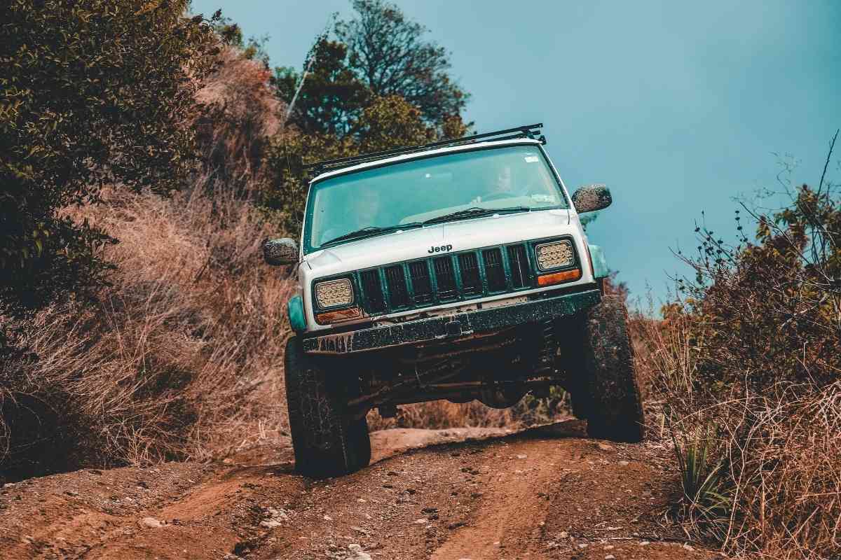 What happens if I drive my car in low gear? Image shows a white Jeep Cherokee traversing muddy terrain