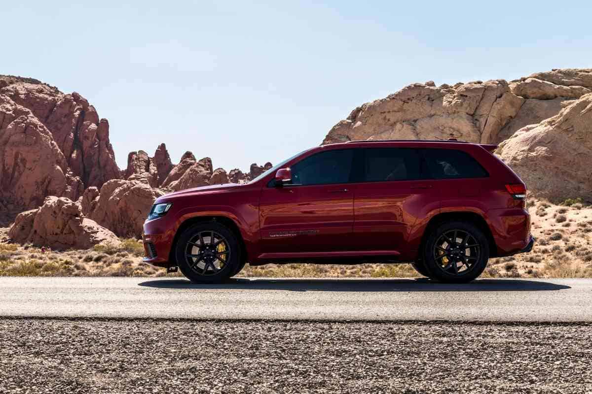 Image for "Best Years For Jeep Grand Cherokee" shoes a red Cherokee against a desert mountain road