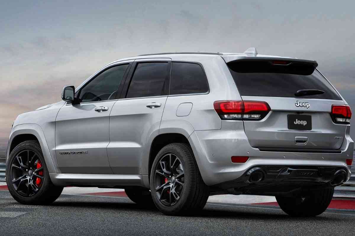 Image for: "best years for Jeep Grand Cherokee" shows a platinum-colored Grand Cherokee from the rear, with racing rims and double muffler