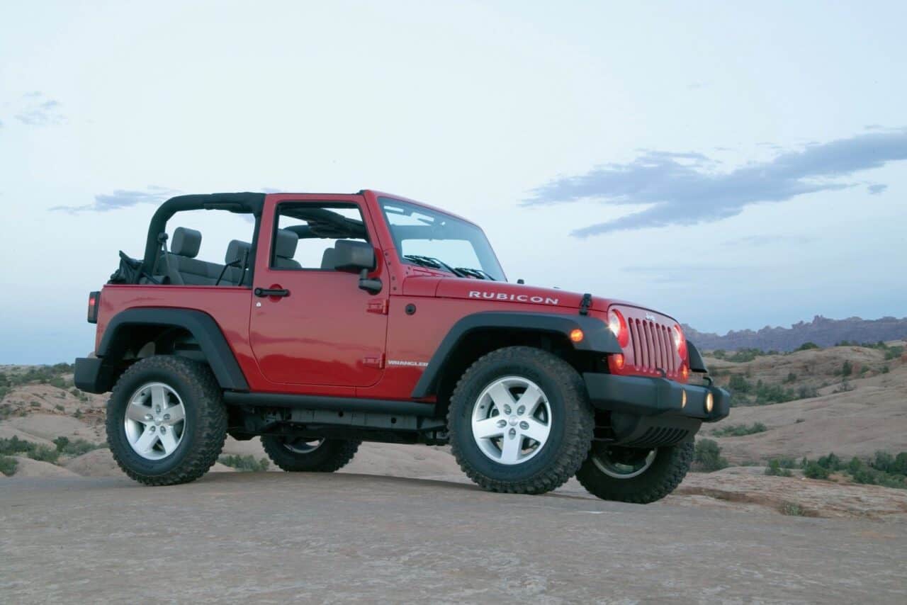 The 2007 model year is one of the Jeep Wrangler model years you should avoid. A two-door Rubicon in red is on a boulder in a desert background. 