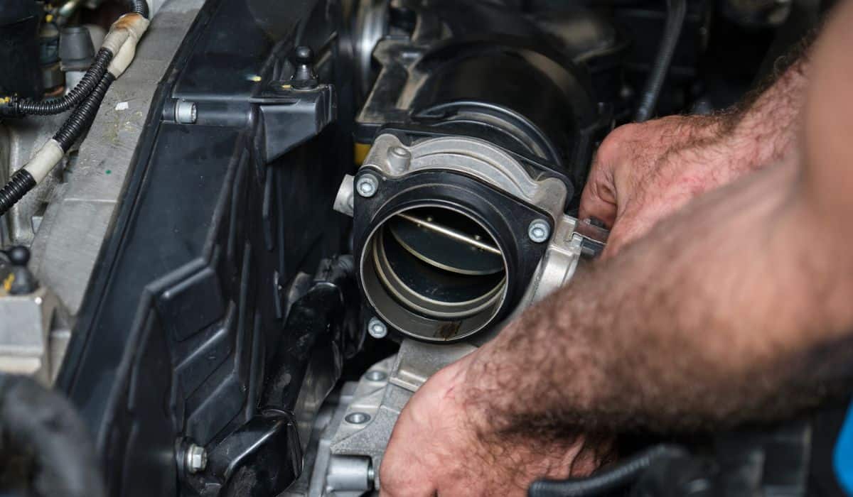 Car mechanic hands replacing engine throttle body