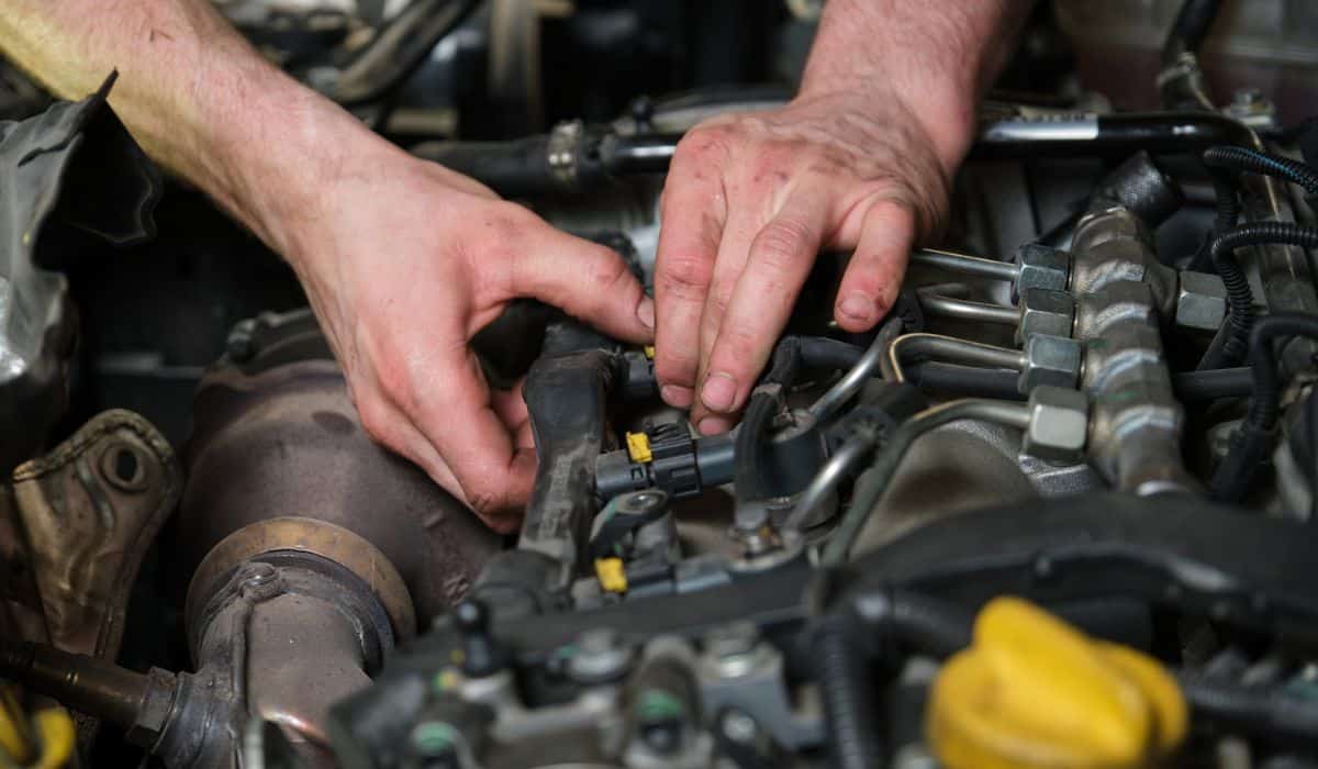 Close up of car mechanic hands removing fuel injectors