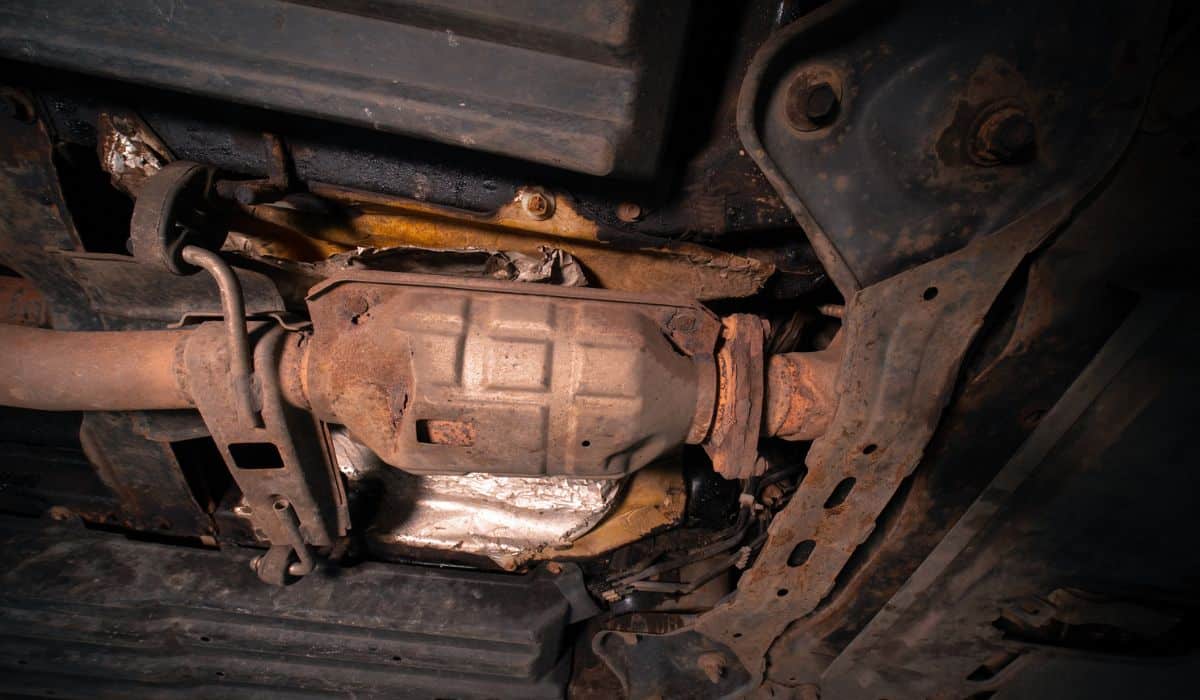 Close-up on the part of the bottom of the car from the front of the exhaust pipe and the catalyst disassembled during the repair