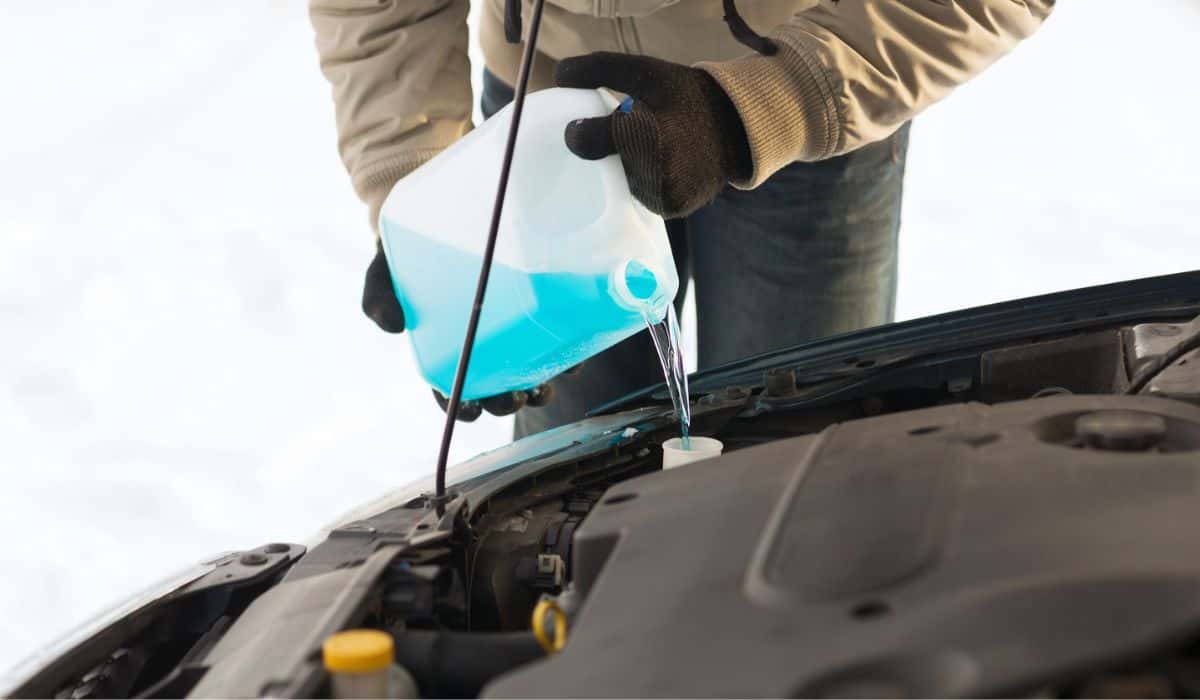 Closeup of man pouring antifreeze into water tank