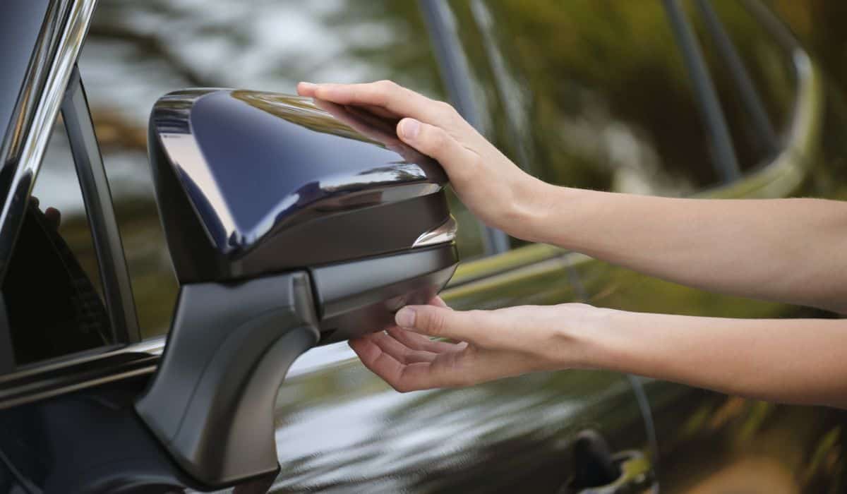 Driver hands adjusting side view mirror of a car