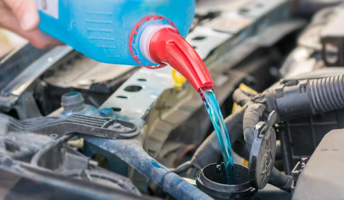 Filling the water tank with antifreeze in the engine compartment of a car
