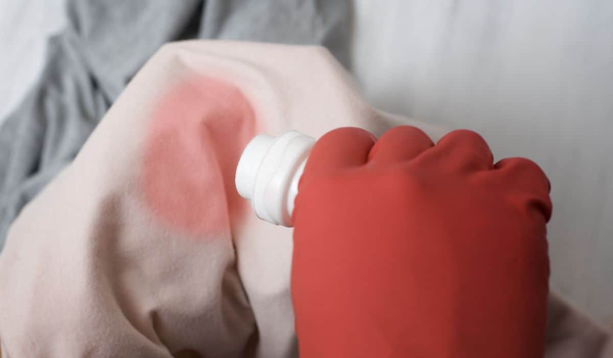 Gloved hand pouring the washing liquid onto the stain on clothes