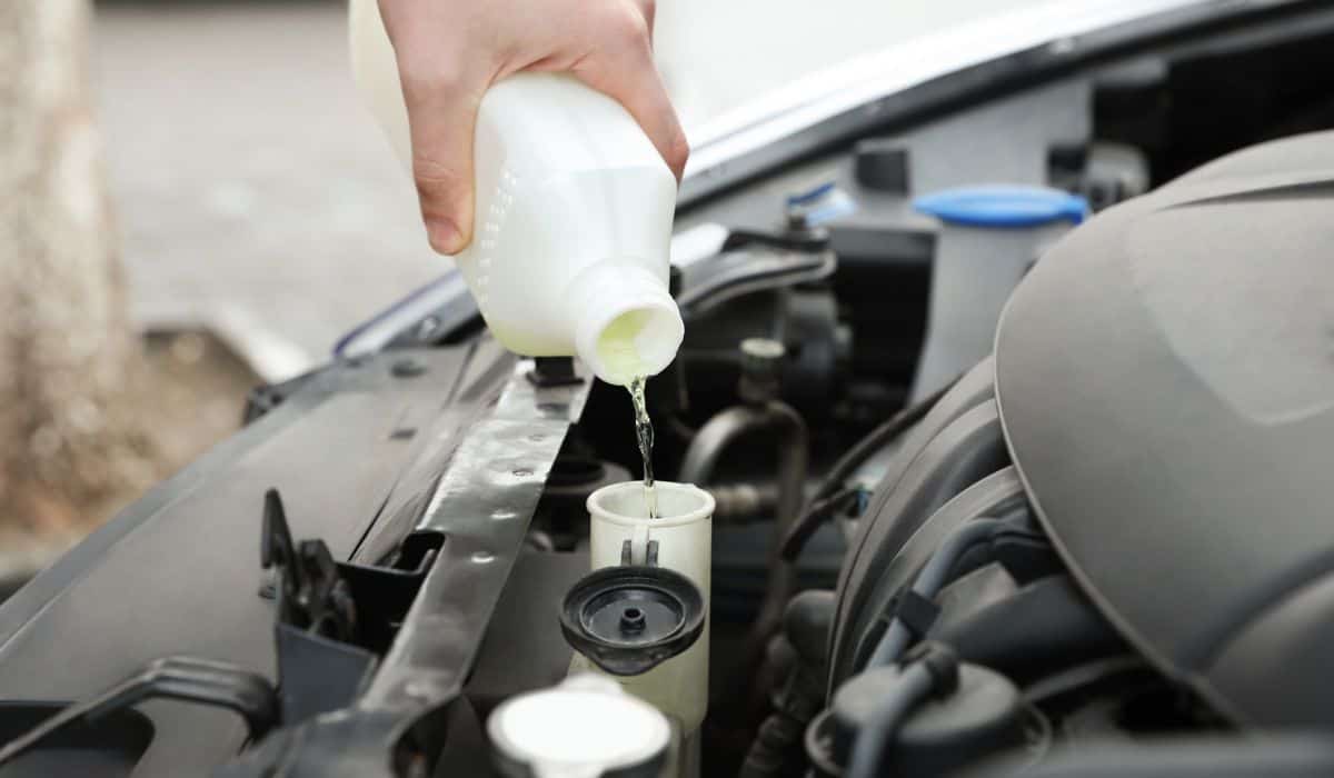 Man filling car radiator with antifreeze outdoors closeup