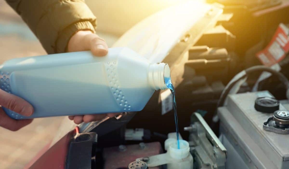 Man filling car radiator with antifreeze outdoors