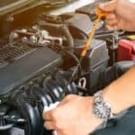 Man or auto mechanic worker hands checking the car engine oil and maintenance. Image for the article: car maintenance checklist