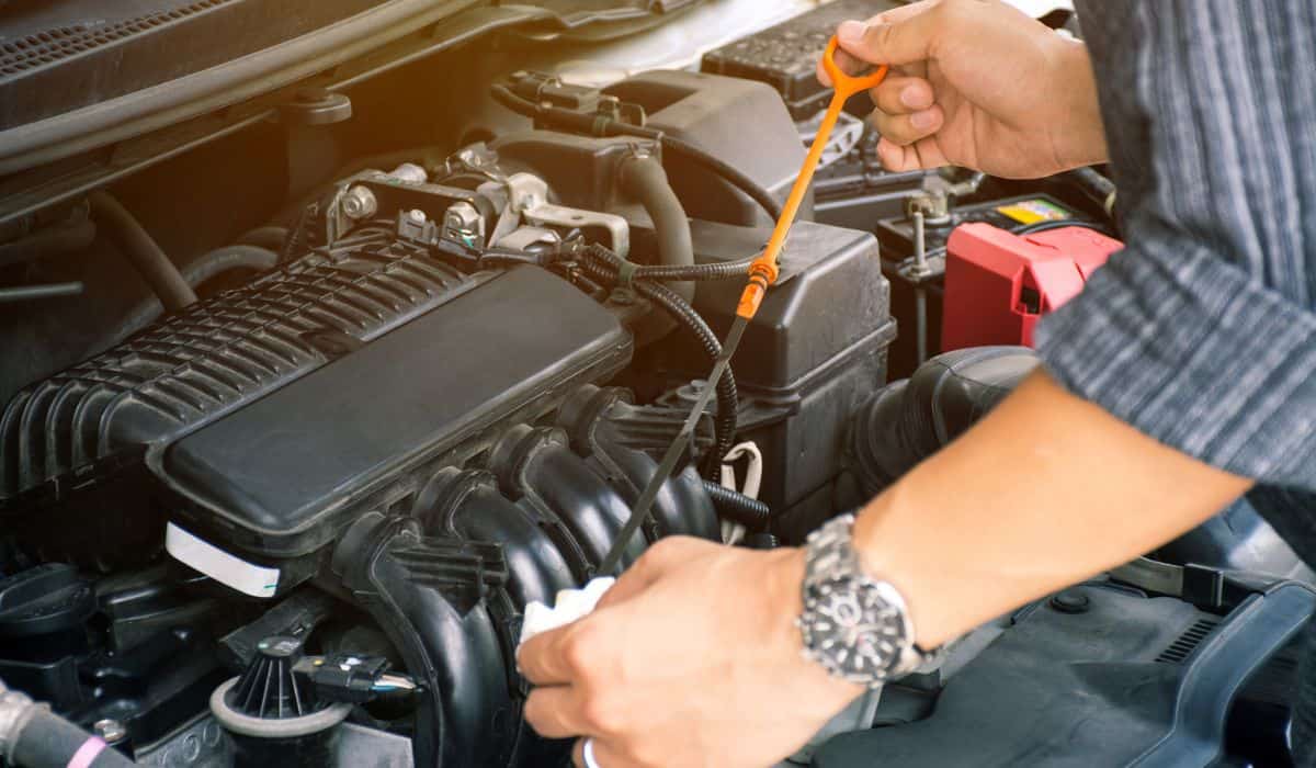 Man or auto mechanic worker hands checking the car engine oil and maintenance. Image for the article: car maintenance checklist
