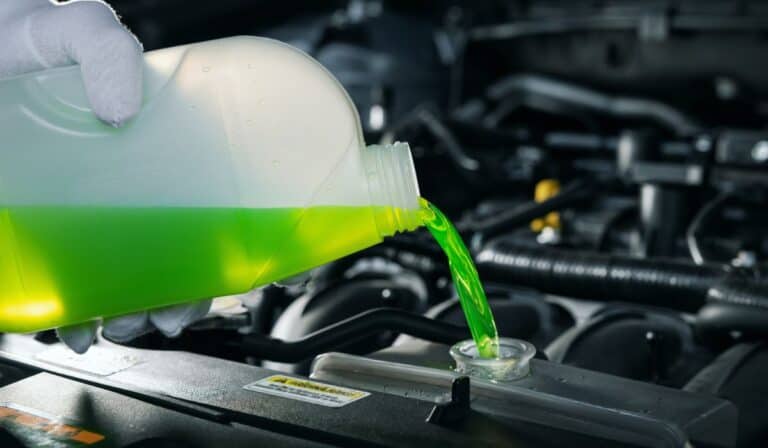 Pouring antifreeze coolant liquid into car engine radiator