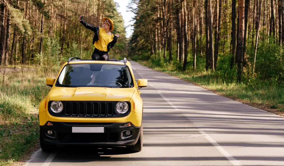 Woman Sitting on Car Sunroof Summer Road Trip