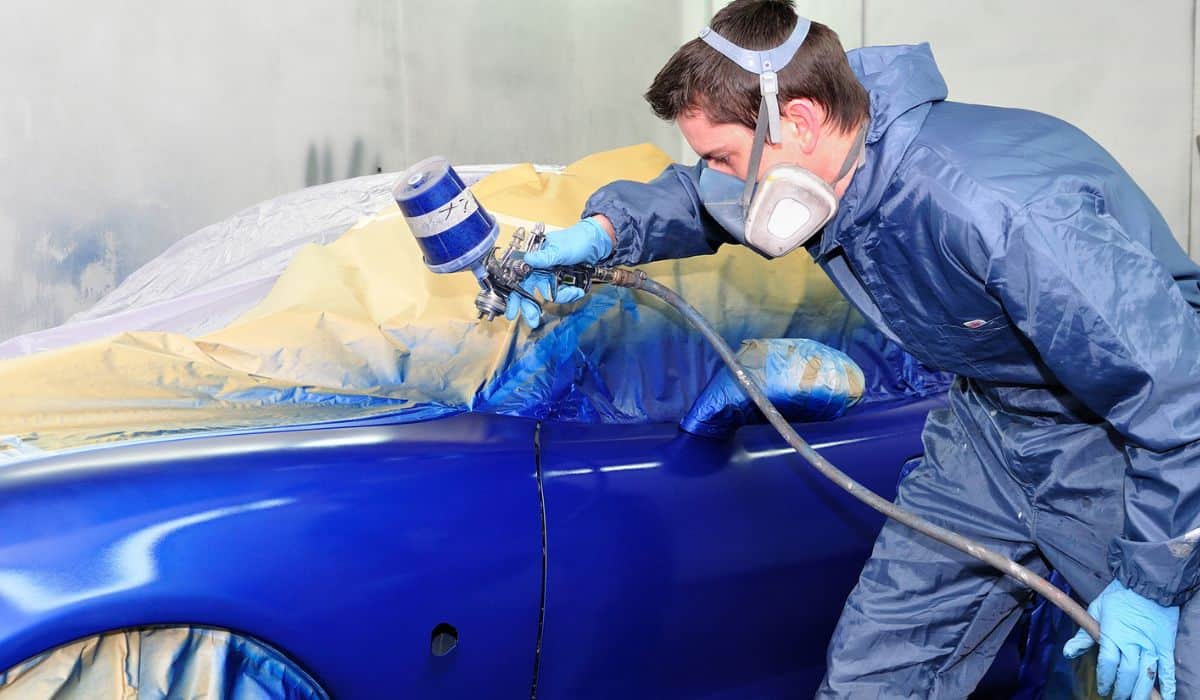 Worker painting a blue car