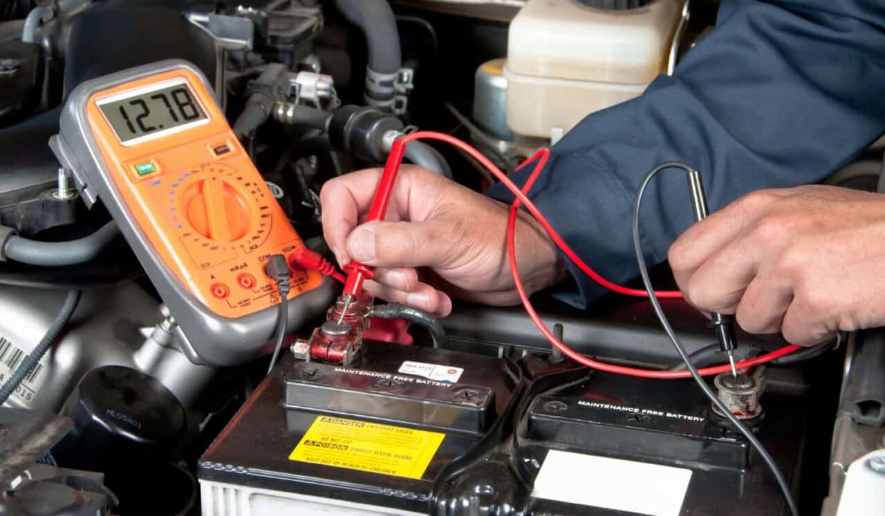 Auto mechanic checking car battery voltage