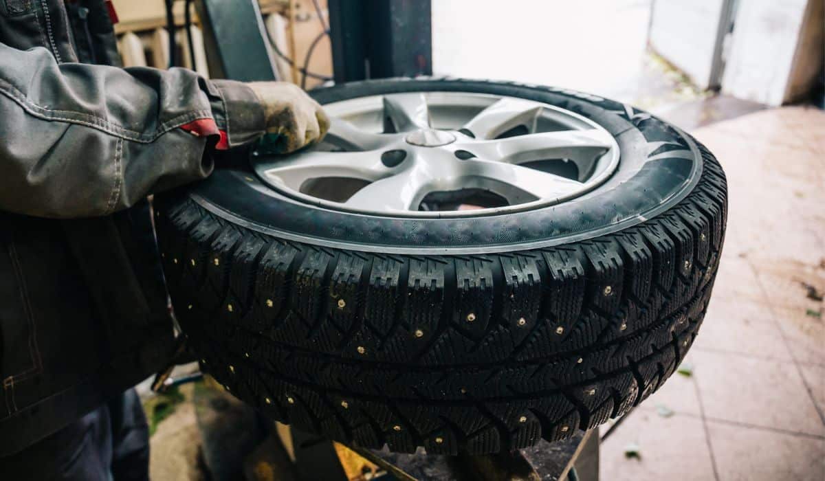 Car mechanic worker doing tire replacement and wheel balancing with special equipment in repair service station