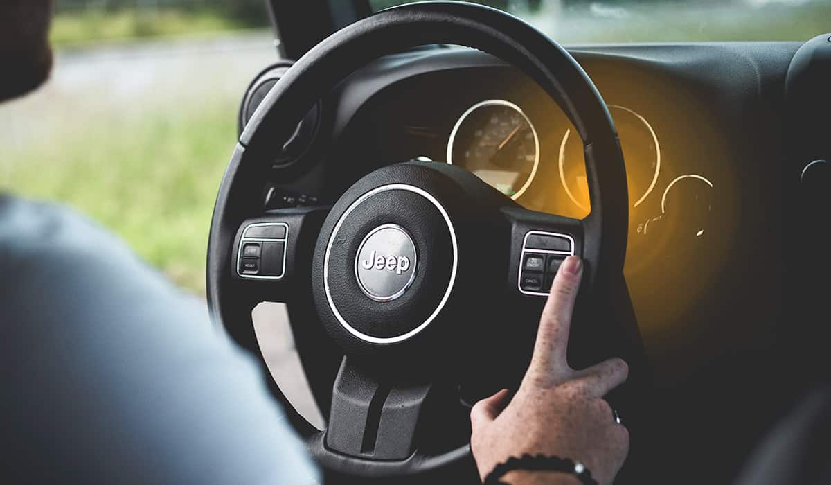 Clsoe up of Jeep steering wheel with a flashing light from the dashboard