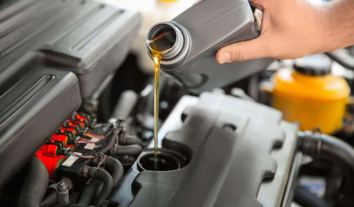 Mechanic pouring oil into car engine