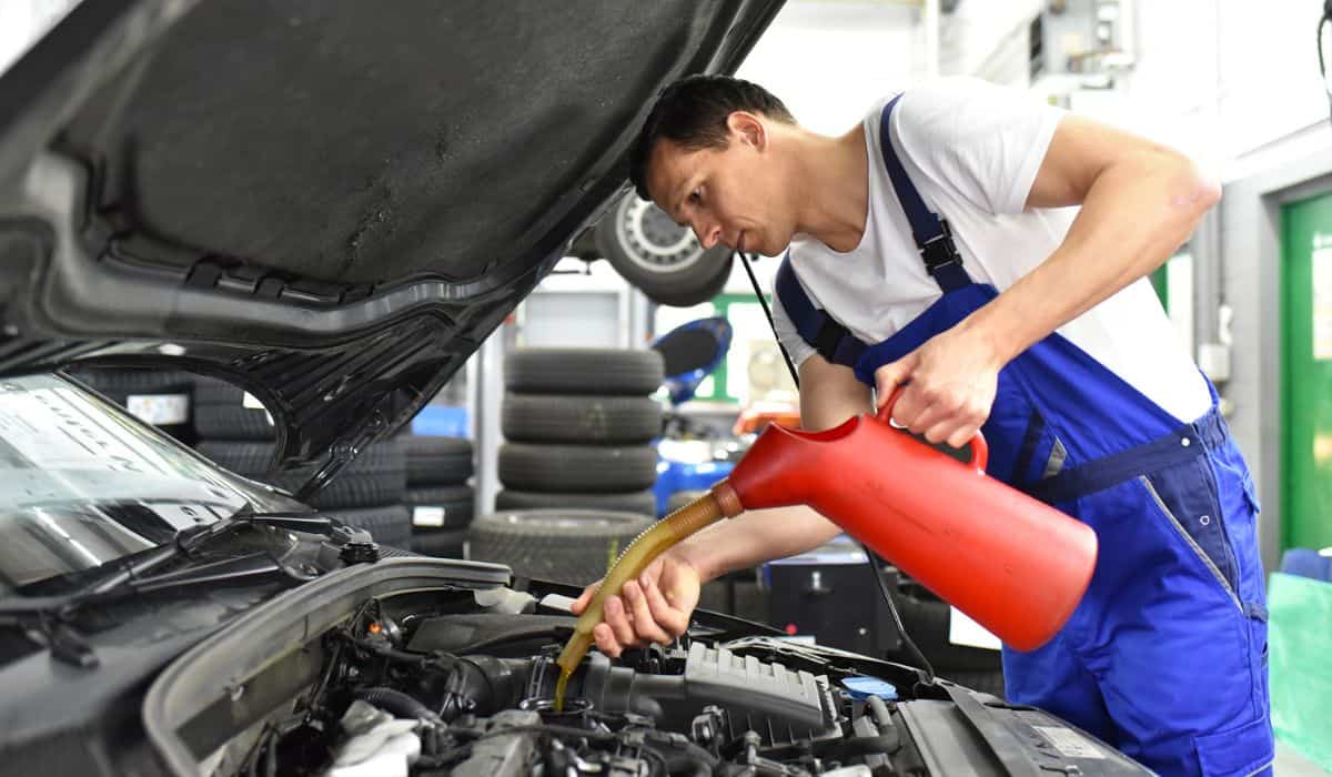 Oil change from the engine of a car in a workshop by a professional mechanic