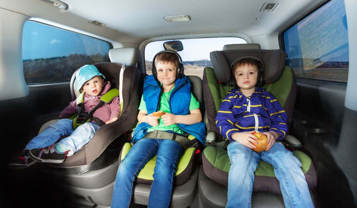 Three happy boys sitting in safety car seats