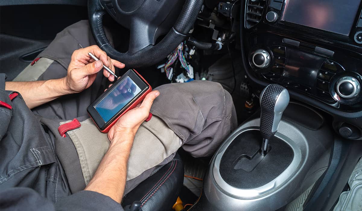 technician with vehicle scanner sitting in interior of the car