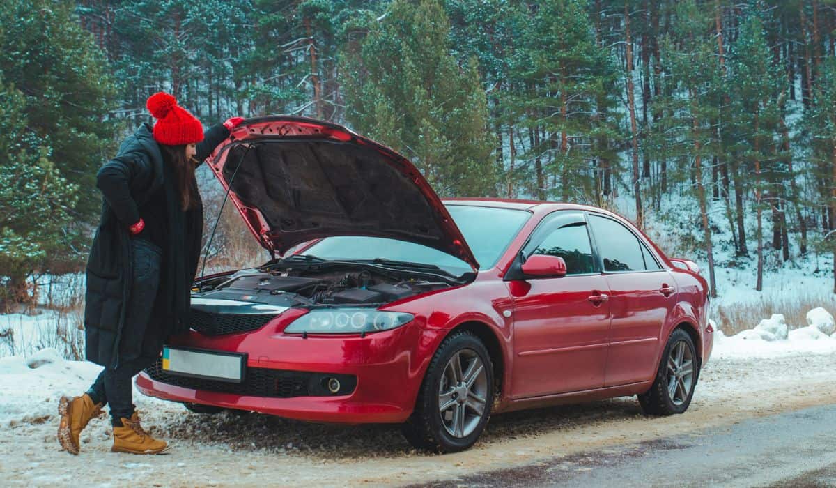 woman looking at engine broken car at winter road side