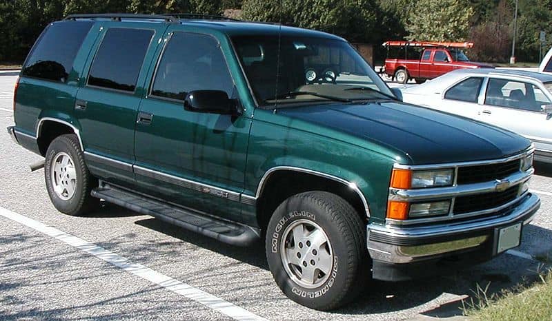 Image for: Best and Worst Chevy Tahoe years shows a green 1999 Chevy Tahoe parked in an urban environment