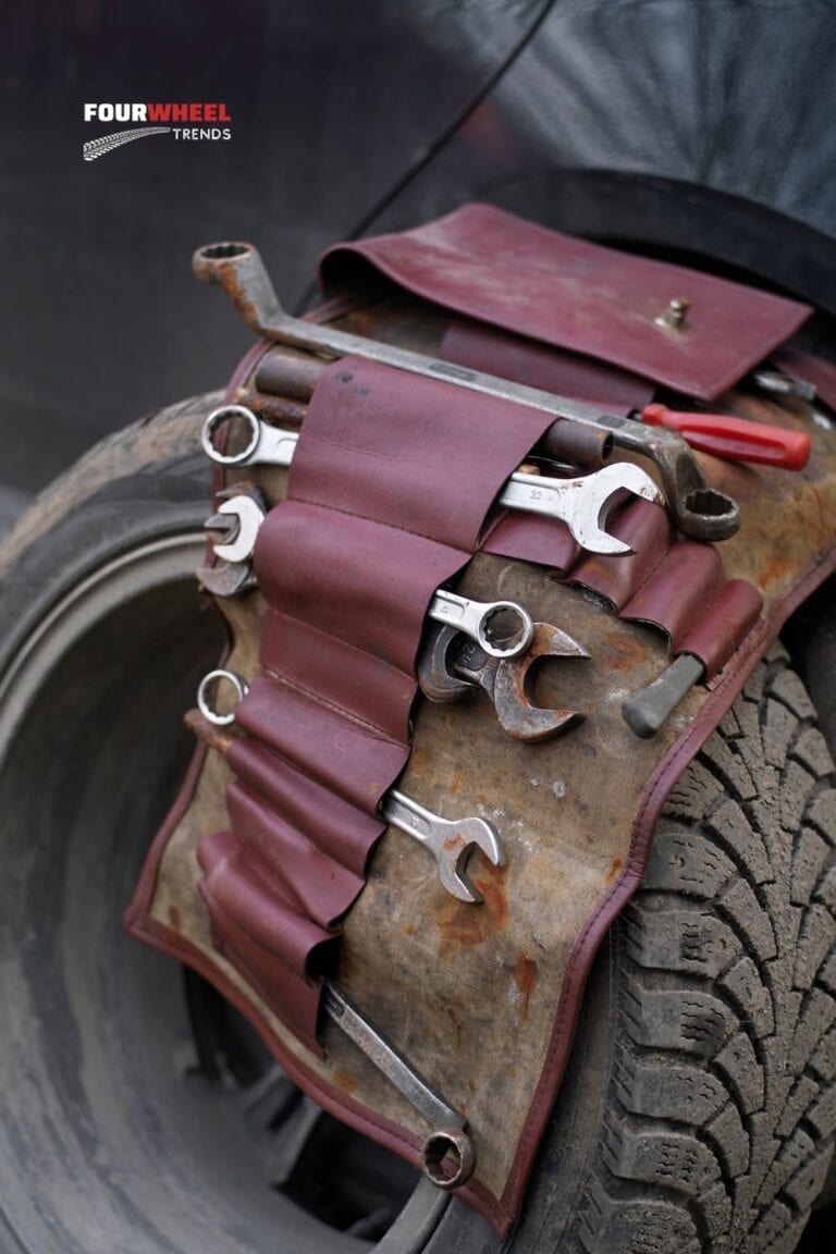 an old tool bag laying over a car tire as if someone is working on their vehicle